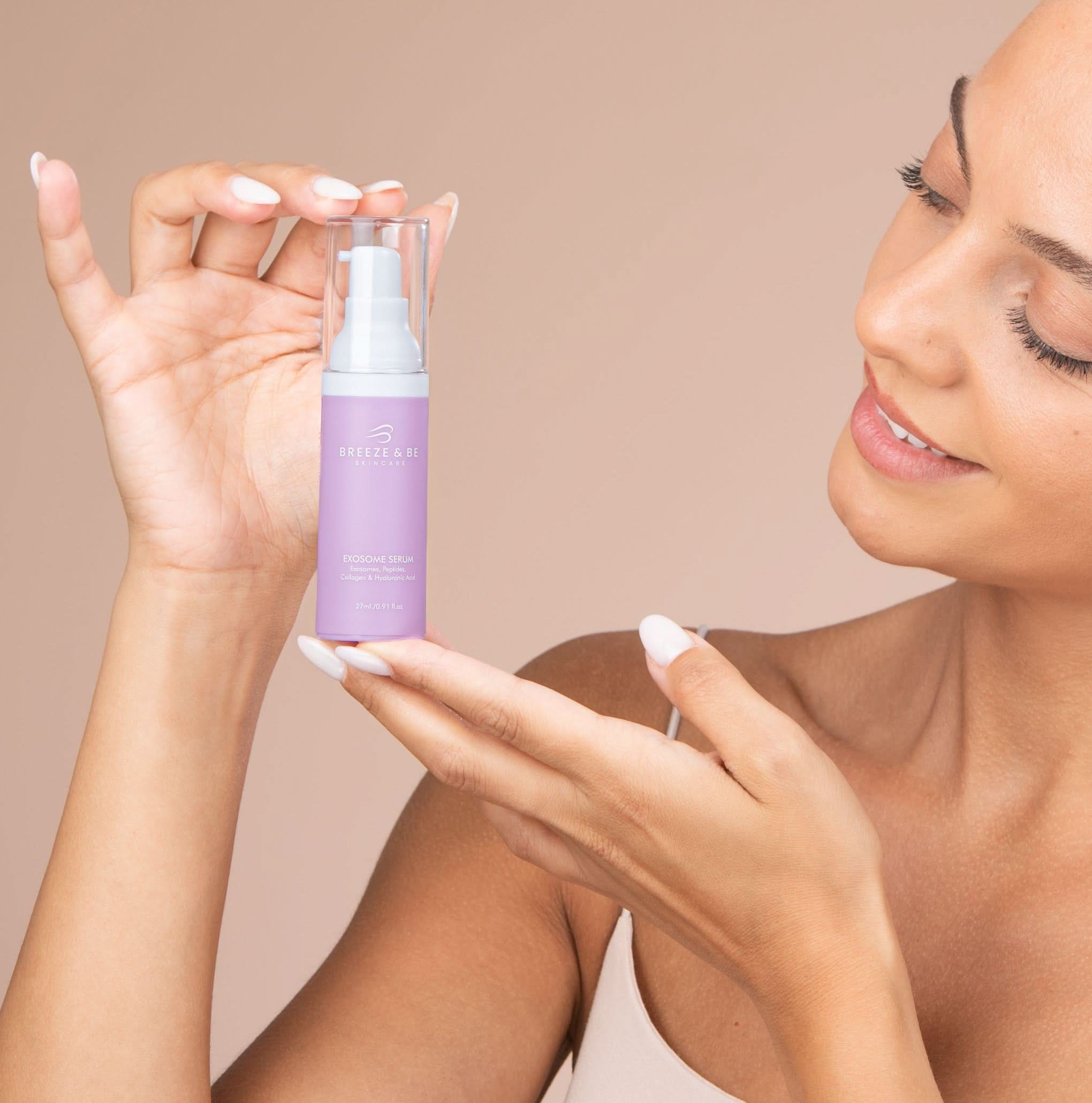 Woman holding a purple skincare bottle with a beige background
