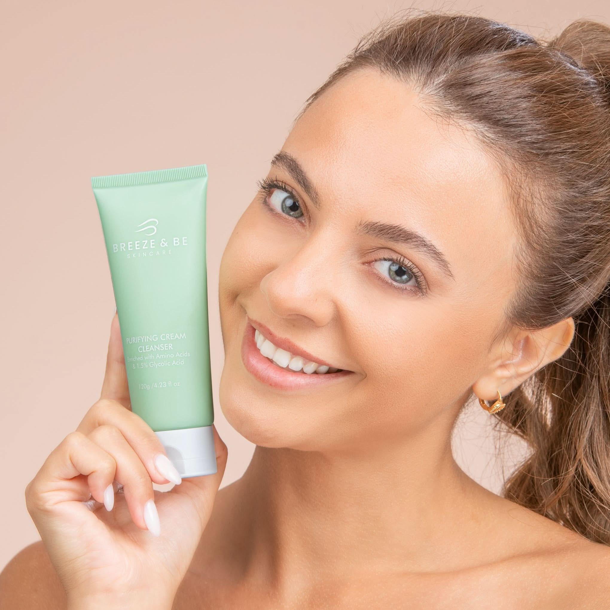 Woman holding a green skincare product with a beige background