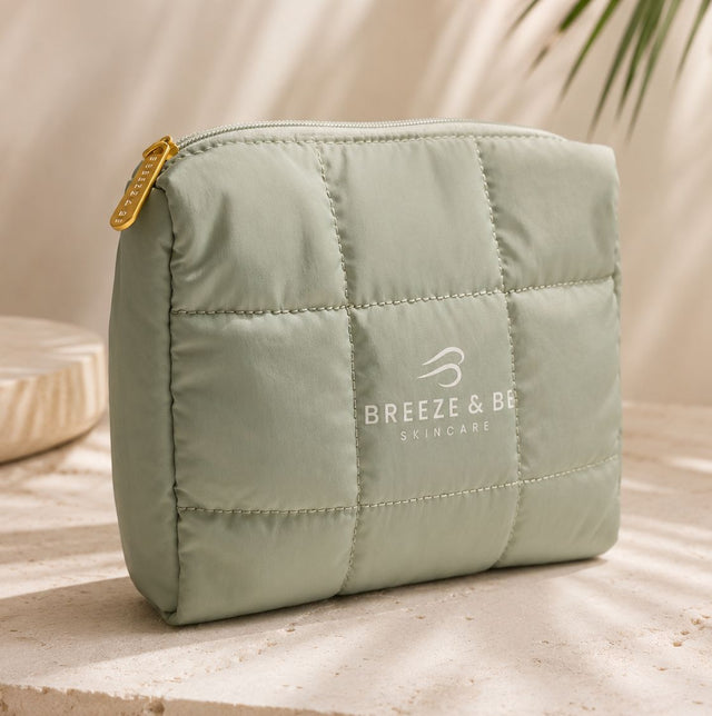 Sage green quilted Breeze & Be skincare pouch beside a palm leaf